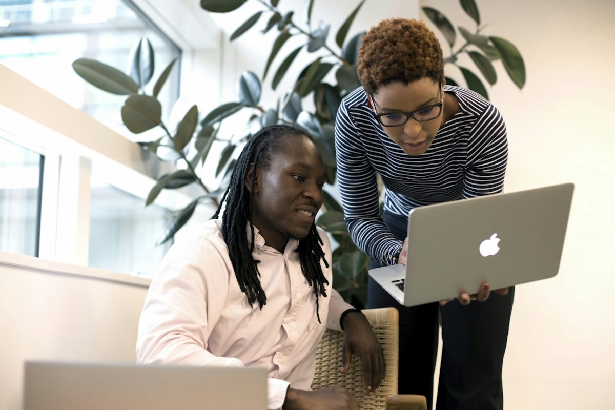 Two colleagues looking at a laptop together in a bright office